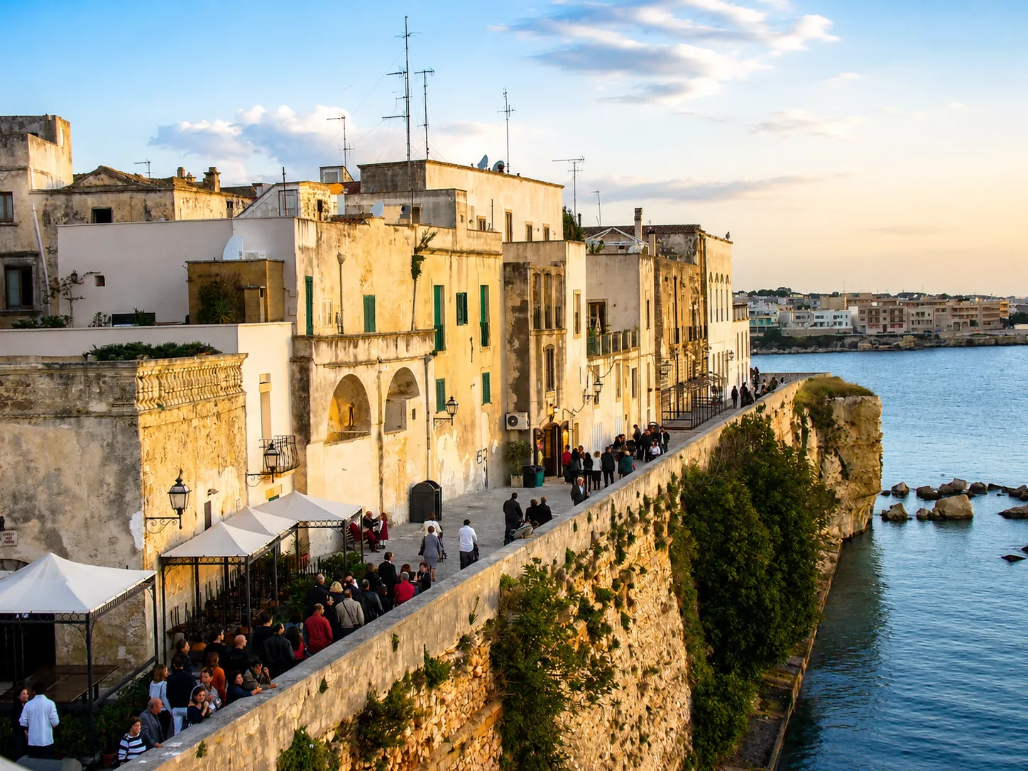Passeggiata sui bastioni di Otranto, tra il centro storico e il mare, nella calda luce del tramonto.