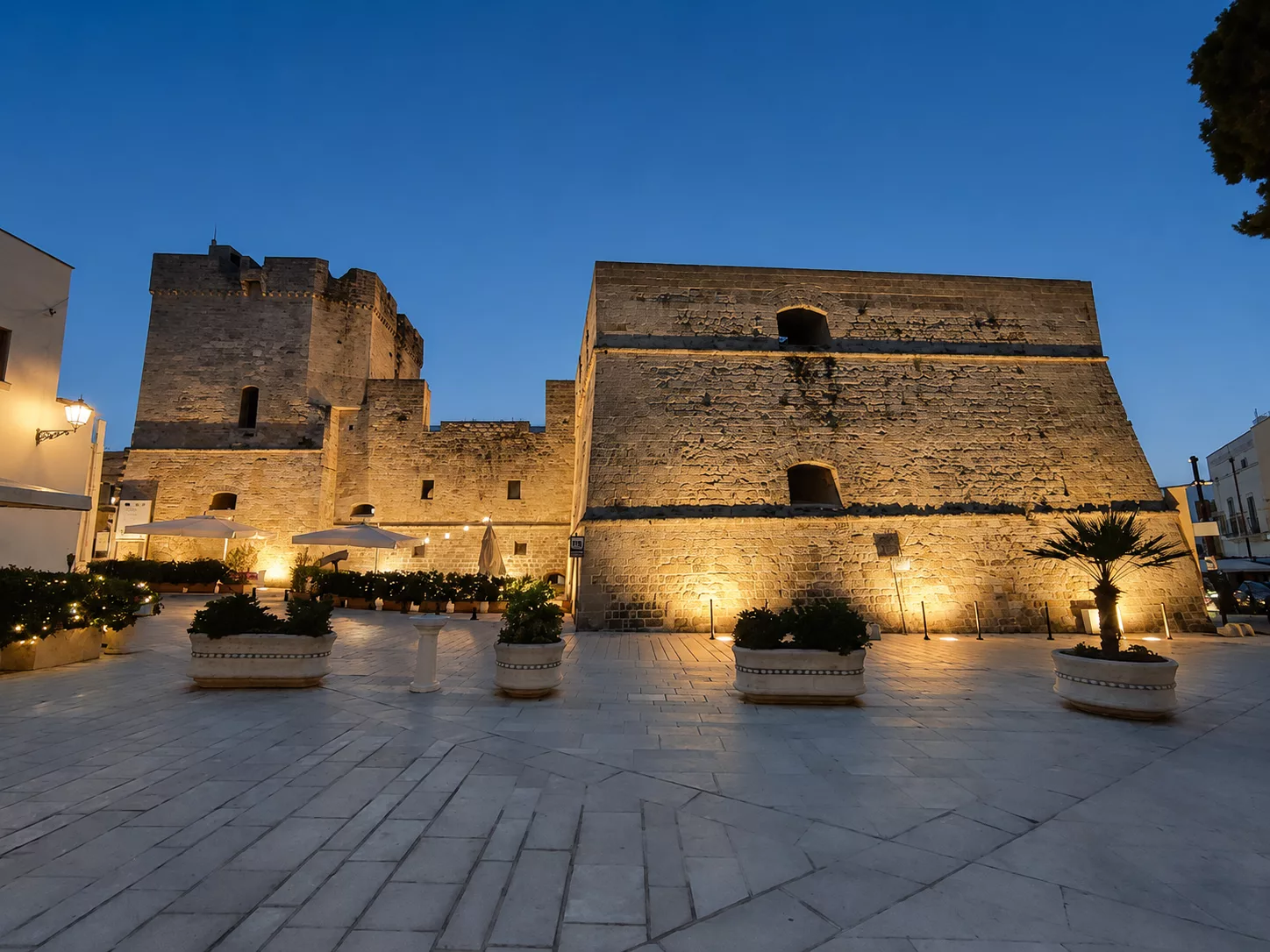 Veduta serale del Castello Aragonese di Castro, illuminato nella quiete della piazza sotto un cielo limpido.
