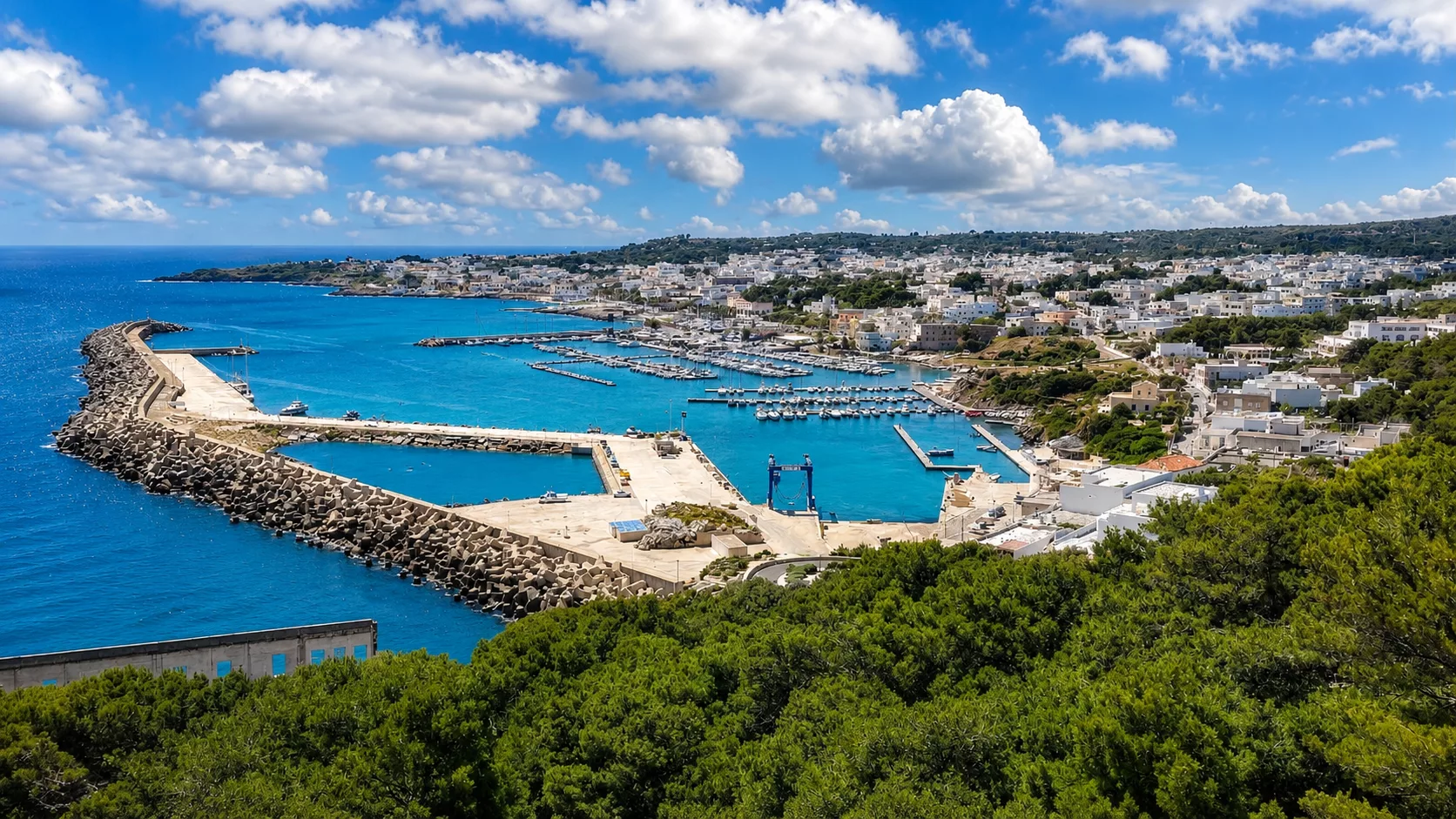 Veduta panoramica del porto turistico di Santa Maria di Leuca, tra mare cristallino, imbarcazioni e case bianche.