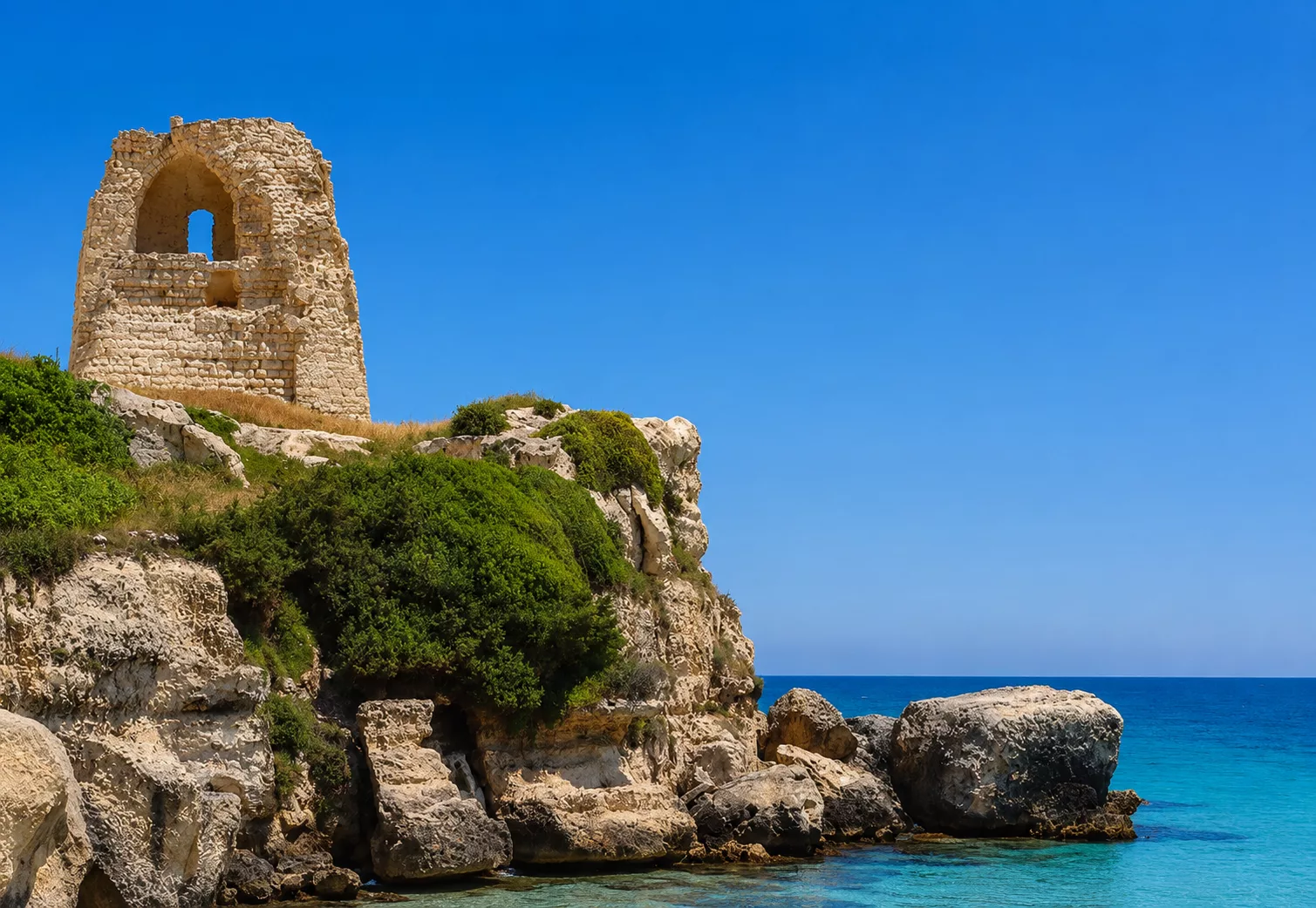 Antica torre costiera di Torre dell’Orso, affacciata su una scogliera rocciosa e sul mare cristallino.